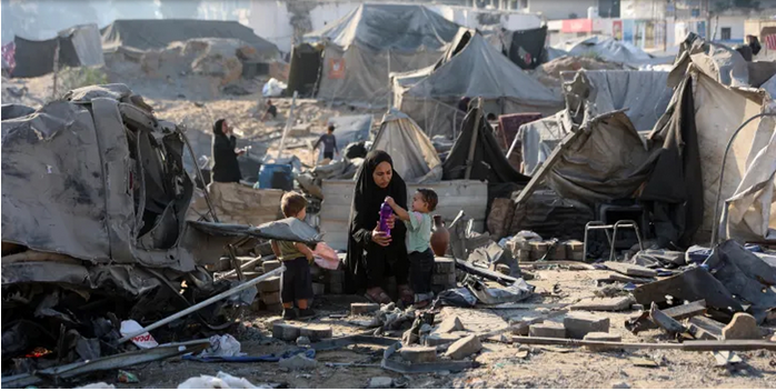 গাজার ধ্বংসস্তূপে নিহতদের লাশ উদ্ধার করছে স্বেচ্ছাসেবকরা, পেছনে ধসে পড়া ভবনের ধ্বংসাবশেষ