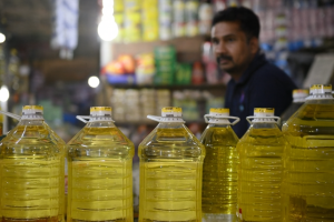 দোকানে ক্রেতা বোতলজাত ভোজ্যতেল কিনছেন, নতুন দাম অনুযায়ী লিটারপ্রতি মূল্য বেড়েছে।