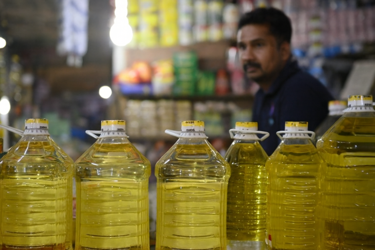 দোকানে ক্রেতা বোতলজাত ভোজ্যতেল কিনছেন, নতুন দাম অনুযায়ী লিটারপ্রতি মূল্য বেড়েছে।