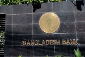 বাংলাদেশ ব্যাংকের ভবনের সামনে একজন মোবাইল ফোনে “সহজক্যাশ” অ্যাপ দেখছেন